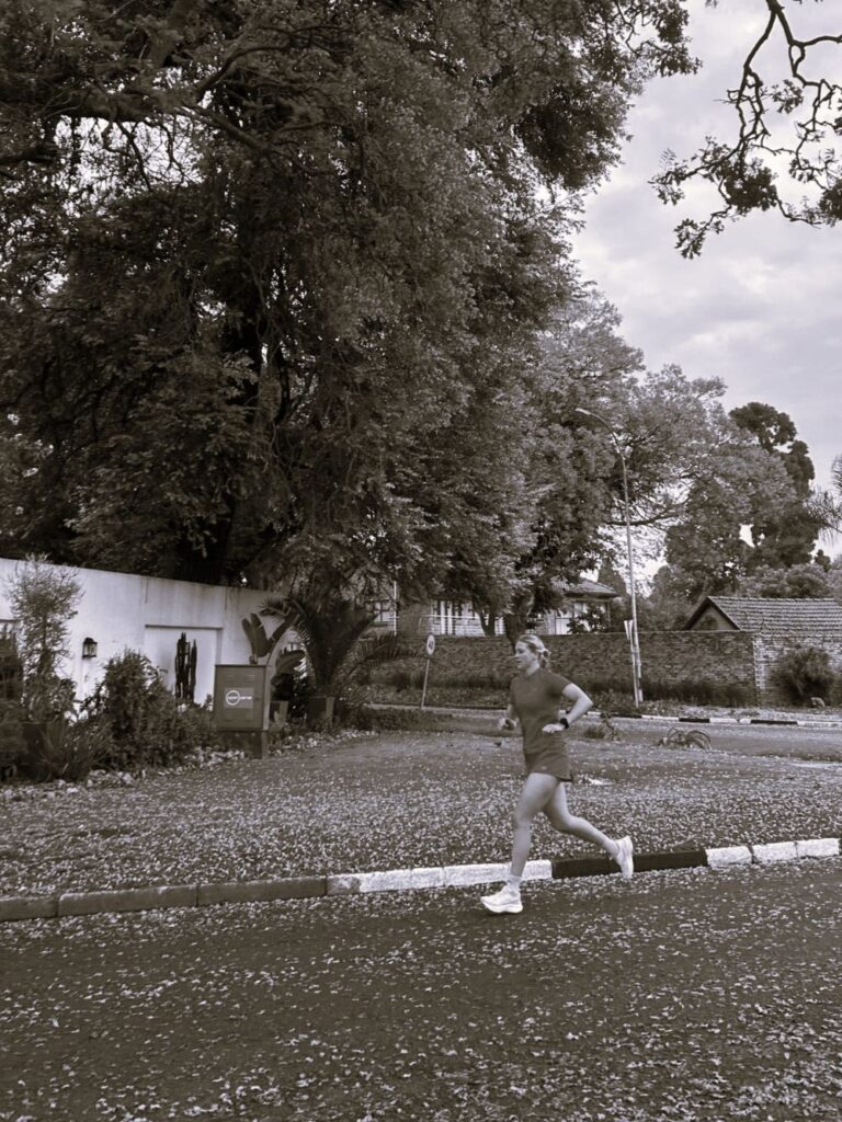 Sarah running in Johannesburg against a backdrop of Jacaranda trees, back to triathlon training after successful rehab for ITB.